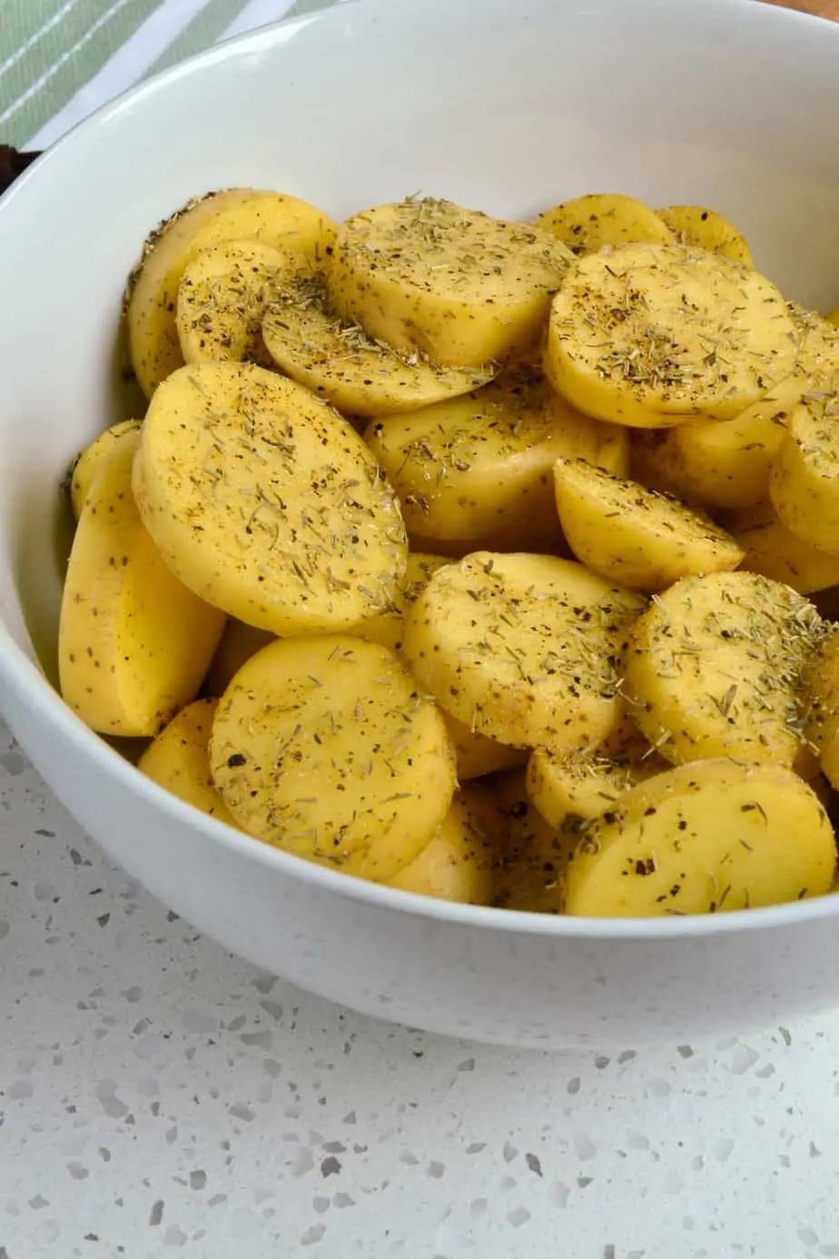 Raw Yukon Gold Potatoes mixed with oil and dried herbs