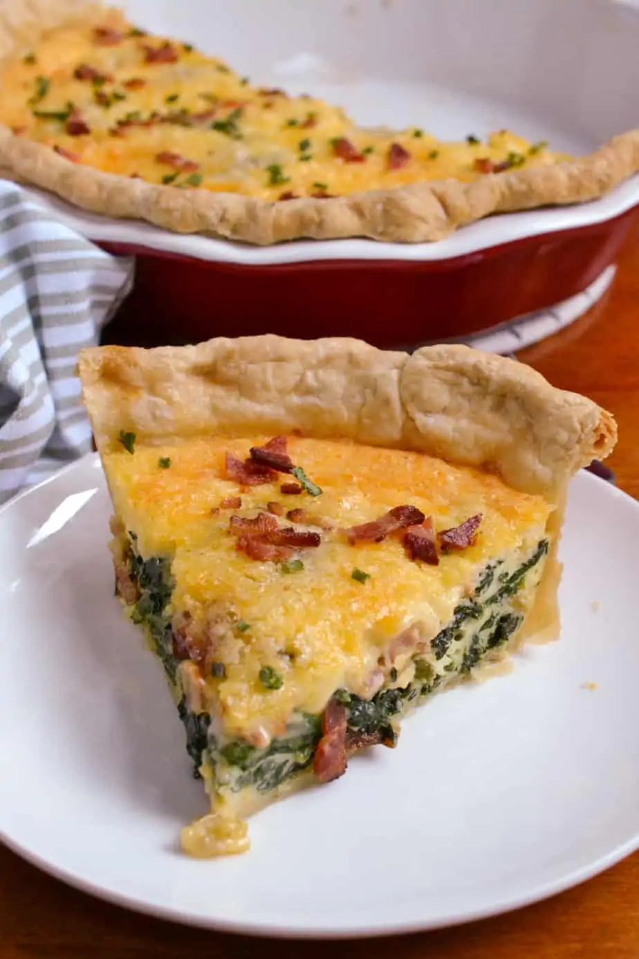 A slice of deep-dish homemade spinach bacon quiche. 