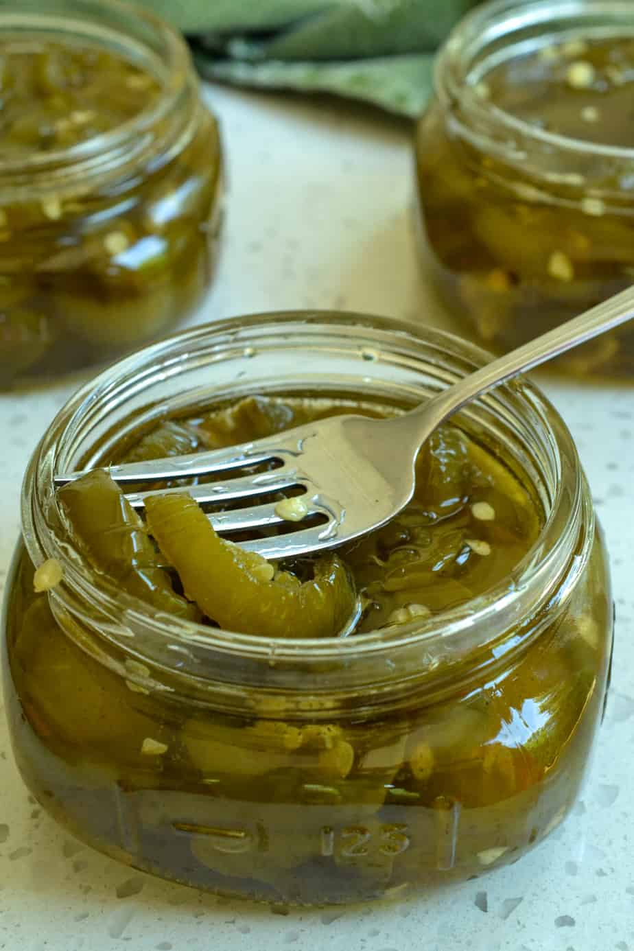 A small jar full of candied jalapenos