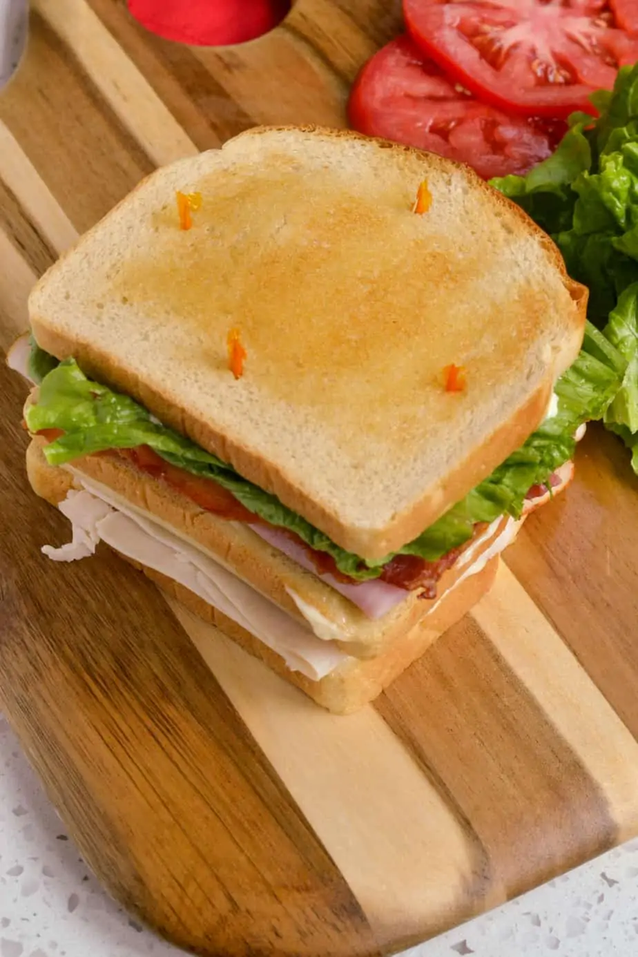 Classic whole club sandwich with lettuce, tomato, turkey, ham, and bacon. 