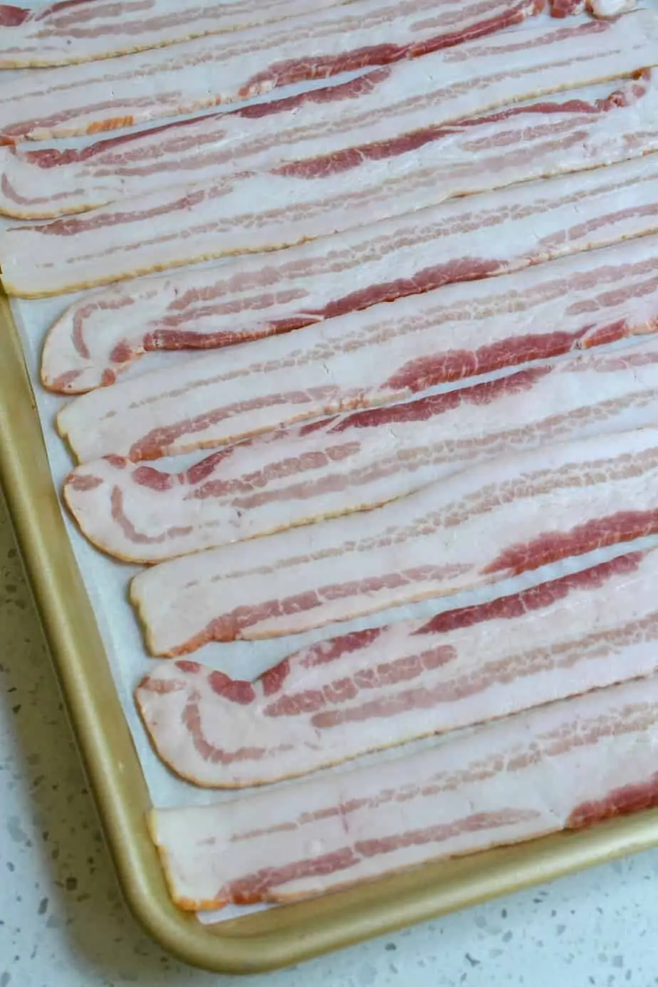 Raw bacon in a single layer on a baking sheet. 