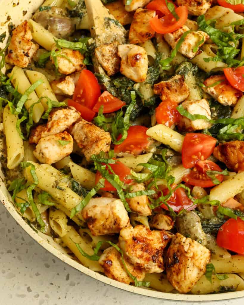 Close up view of chicken pesto pasta in a large skillet.