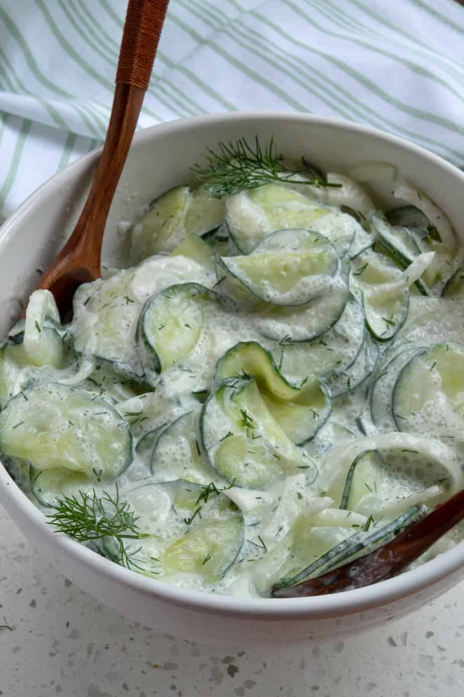 A bowl full of German cucumber salad with onions. 