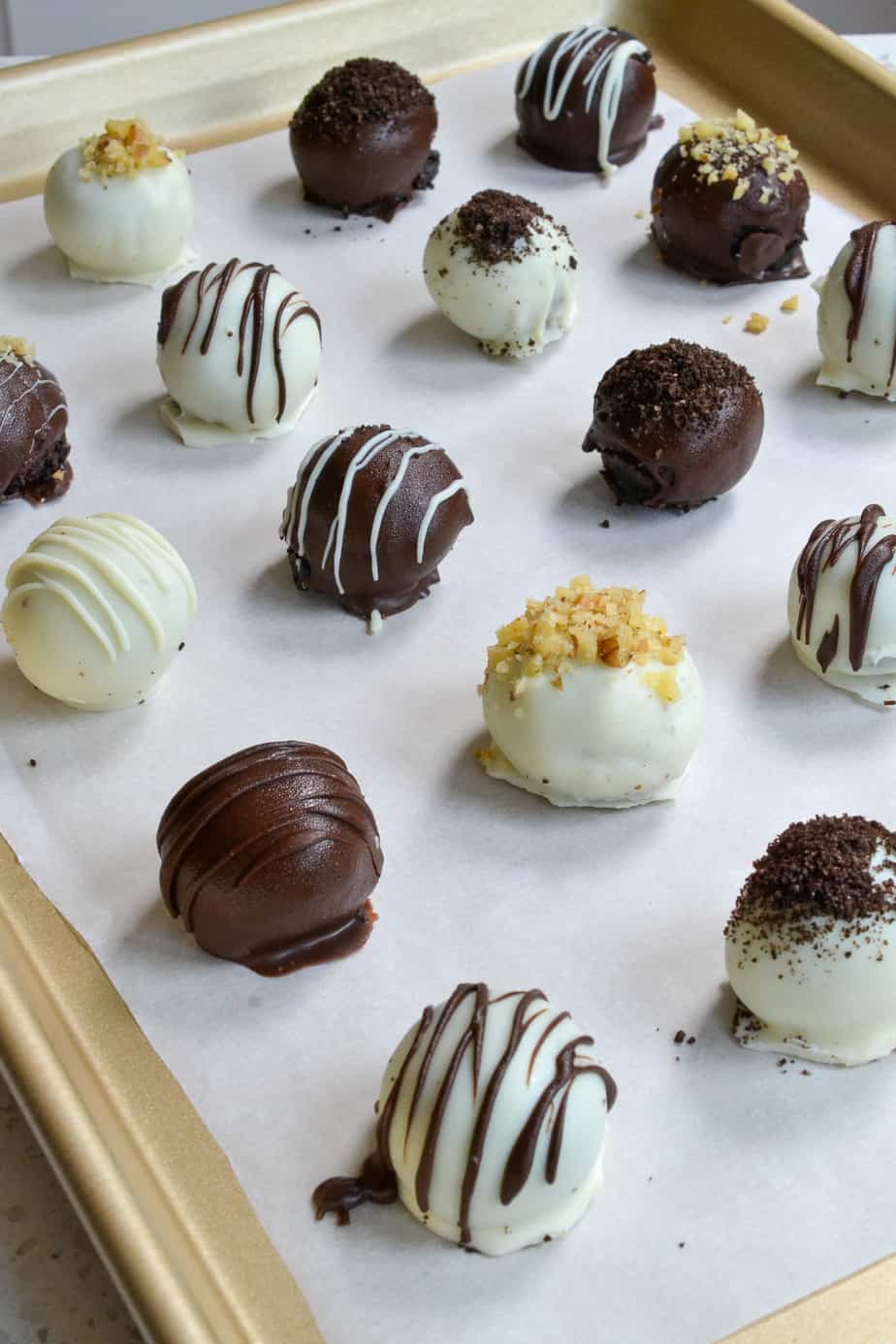 Assorted decorated Oreo truffles on a parchment covered baking sheet. 