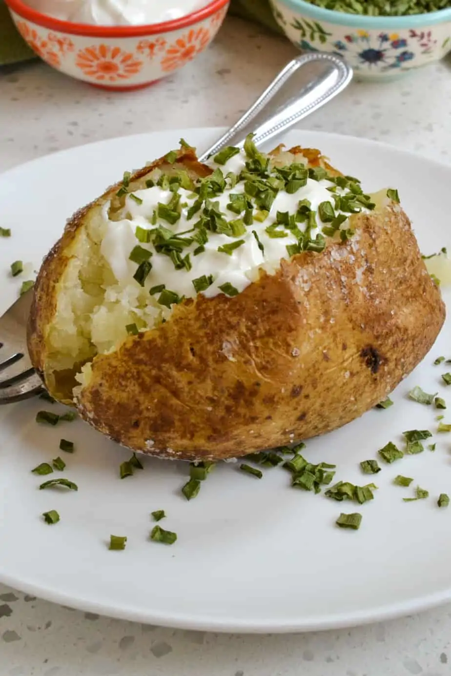 An oven baked potato with sour cream and chives. 