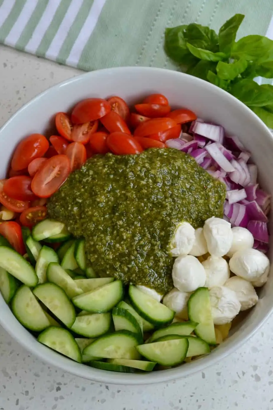 All of the ingredients for the Pesto Pasta Salad in a bowl. 