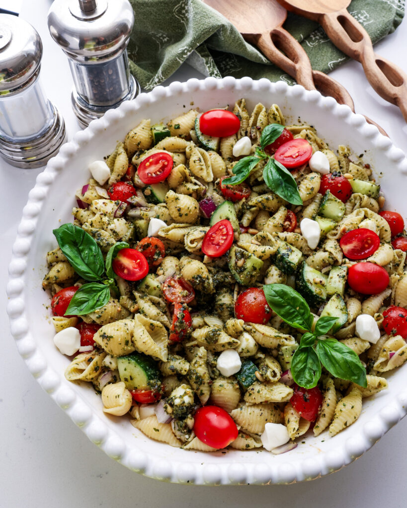 A close up view of a large bowl of pesto pasta salad. 