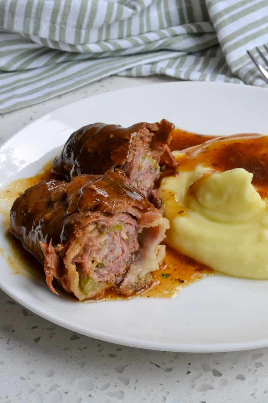 German Beef Rouladen on a plate with mashed potatoes.