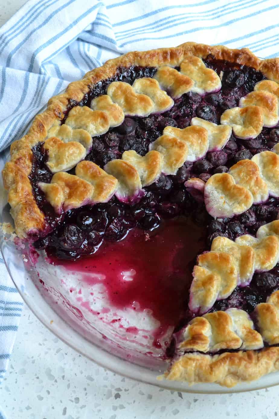 A homemade blueberry pie with a piece sliced out of it. 
