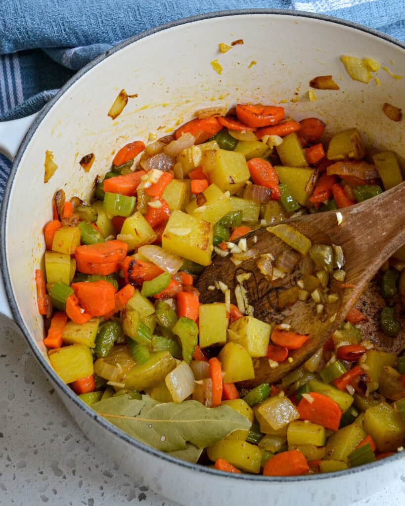 In a Dutch oven or large pot, heat a little oil, add the onions, carrots, and celery, and cook until tender. Add the potatoes, garlic, celery salt, and cayenne pepper, stirring constantly for 1 minute.