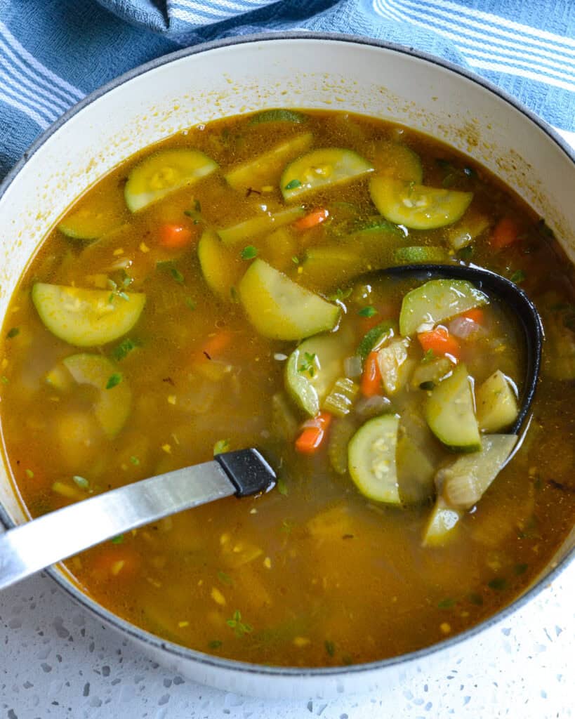 Zucchini Soup in a Dutch oven with soup on a ladle.