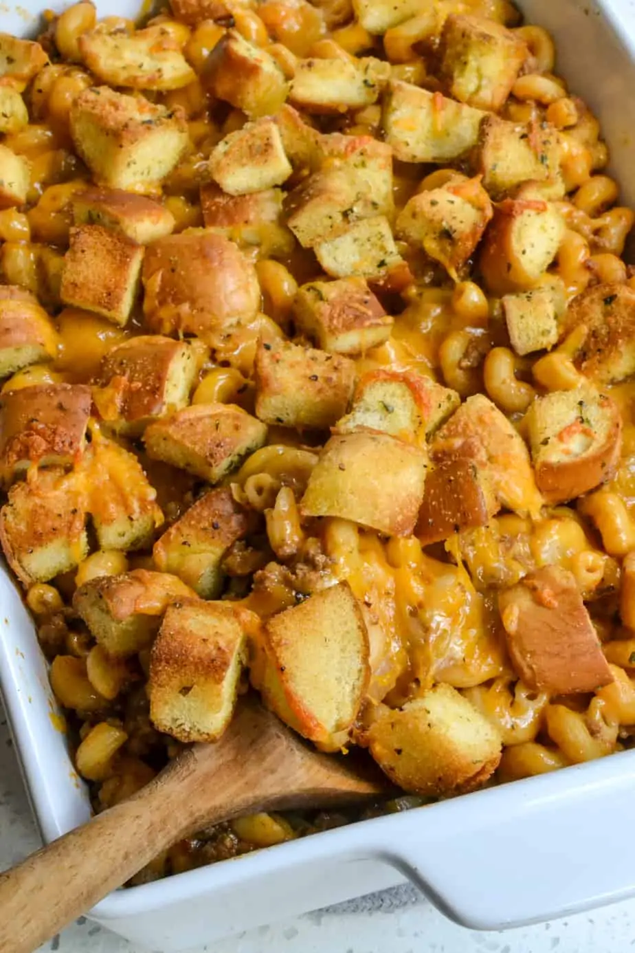 This amazing Cheeseburger Casserole combines all the best flavors of cheeseburgers like ground beef, onions, garlic, ketchup, mustard, and Colby into a cheesy pasta casserole topped with seasoned homemade bun croutons.  