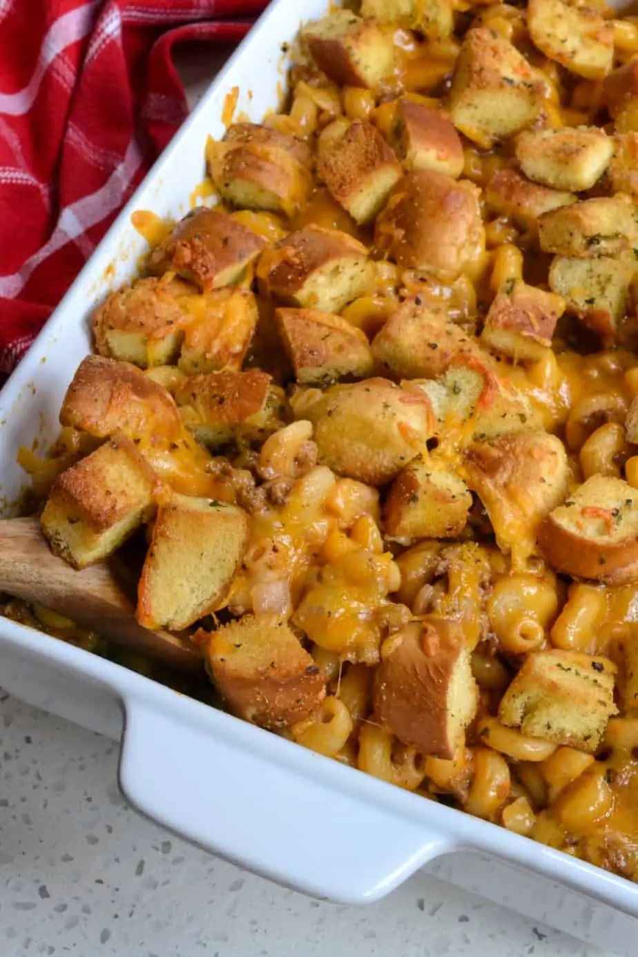A pan full of cheesy hamburger casserole topped with fresh homemade bun croutons. 