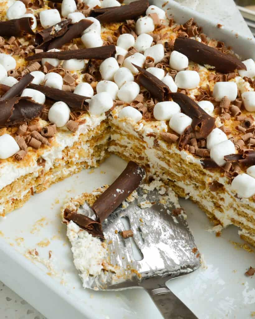 A pan full of Icebox Cake made with graham crackers and whipped cream with a serving utensil.