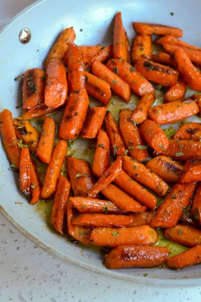 Honey roasted carrots with fresh thyme in a skillet. 