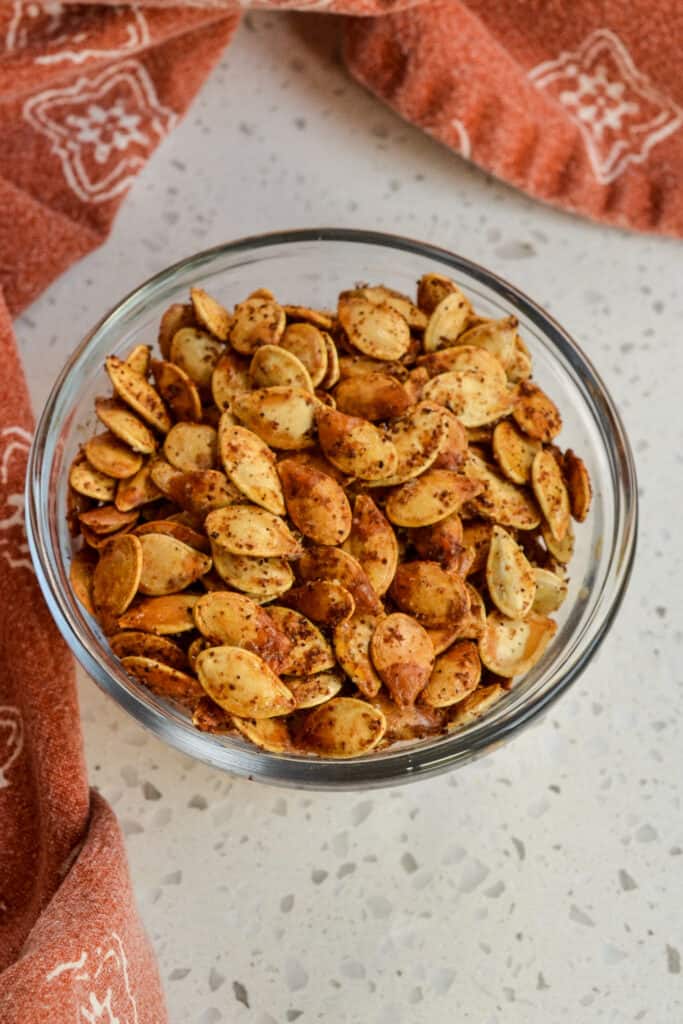 A small glass bowl filled with roasted pumpkin seeds. 