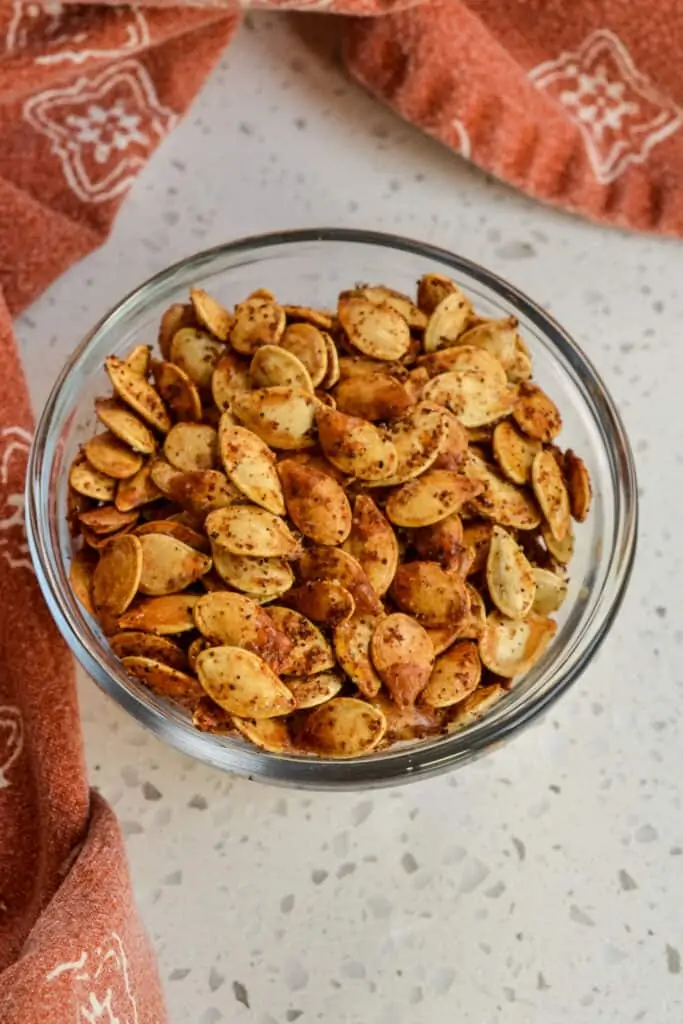 A small glass bowl filled with roasted pumpkin seeds. 