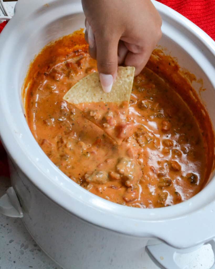 A crock full of rotel dip made with pork sausage, tomatoes, and velveeta cheese. 