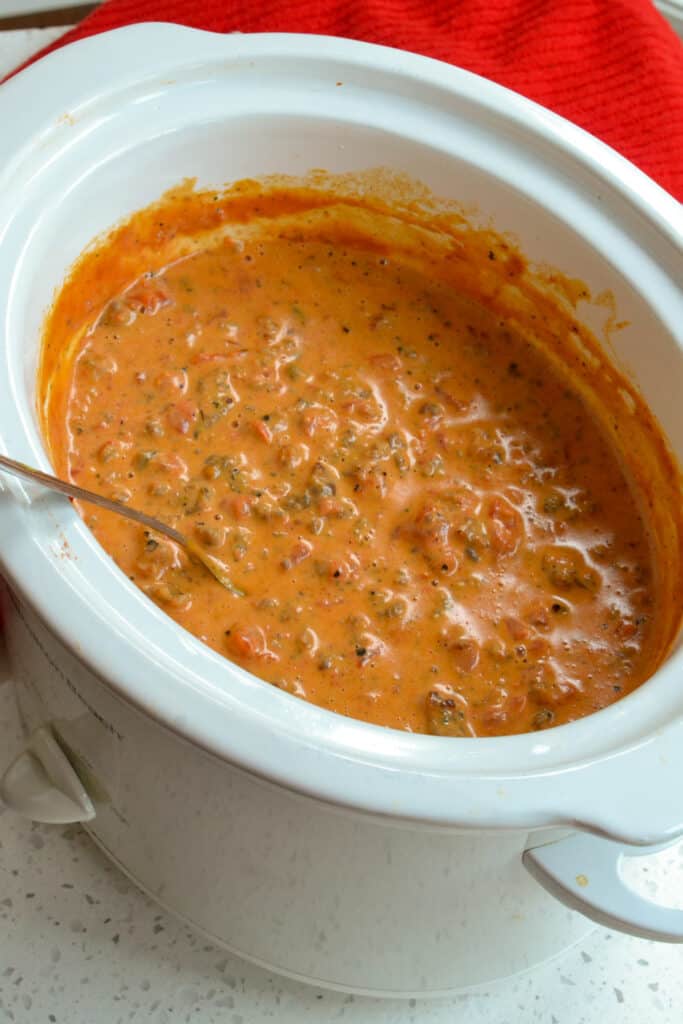 A crock full of browned sausage, melted cheese, and tomatoes. 