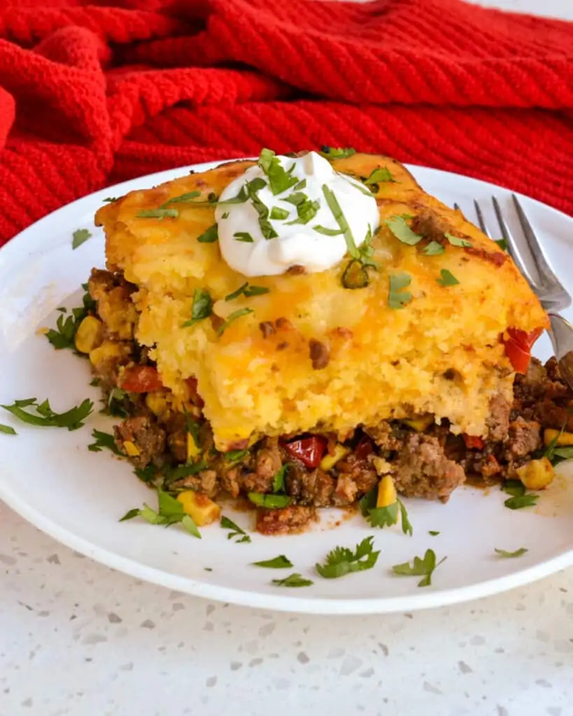 A slice of Tamale Pie with sour cream and chopped cilantro. 