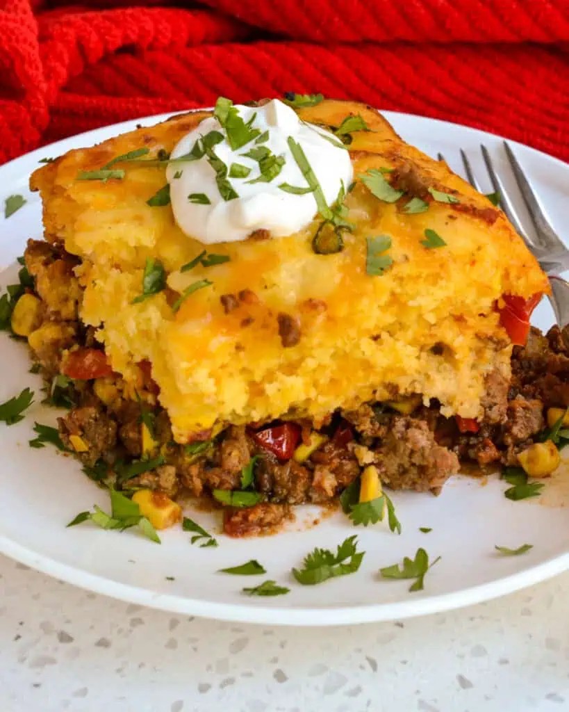 A slice of Tamale Pie with sour cream and chopped cilantro.