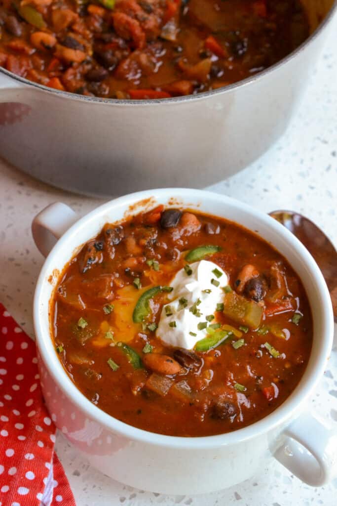 A bowl of chili topped with sour cream, cheddar, and minced jalapeno.