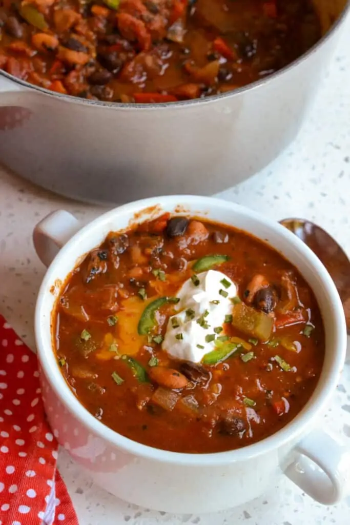 A bowl of chili topped with sour cream, cheddar, and minced jalapeno. 