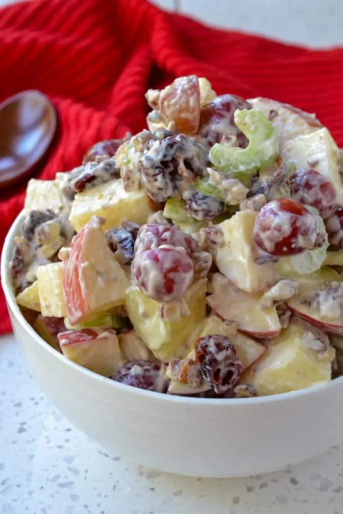 A bowl piled high with fresh apple salad tossed with mayonnaise and brown sugar.  