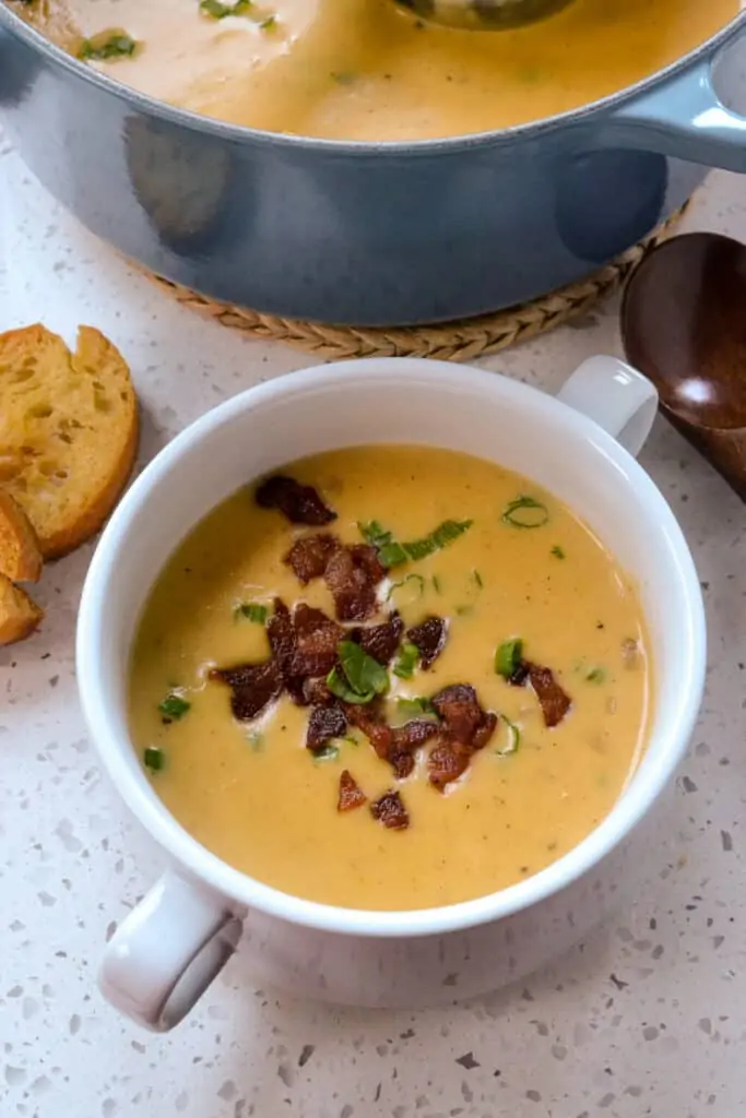 A bowl full of Beer Cheese Soup topped with crisp bacon and green onions. 