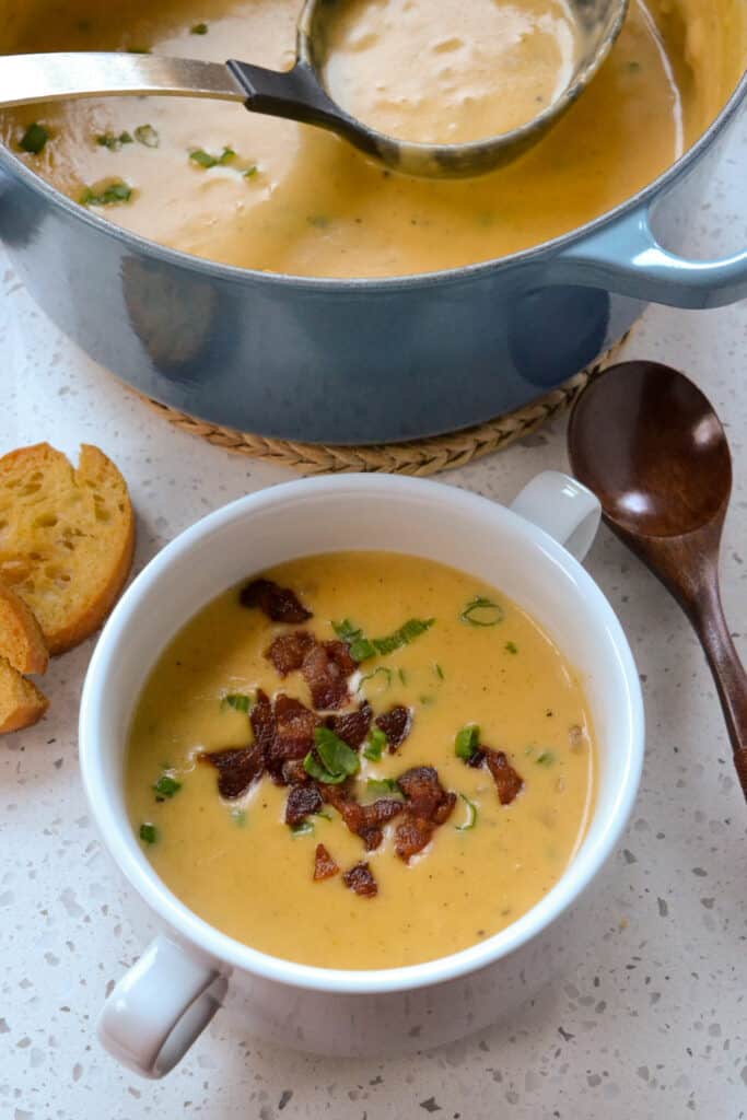Bowl and Dutch Oven full of Irish Beer Cheddar Soup served with crostini
