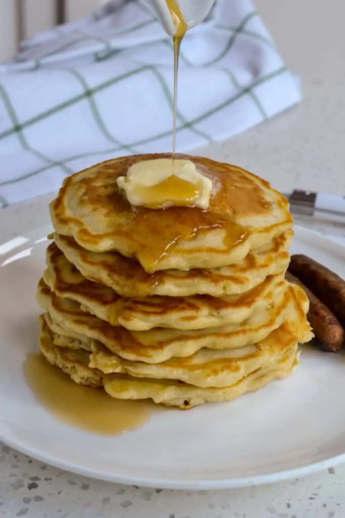A stack of oatmeal pancakes with butter and syrup. 
