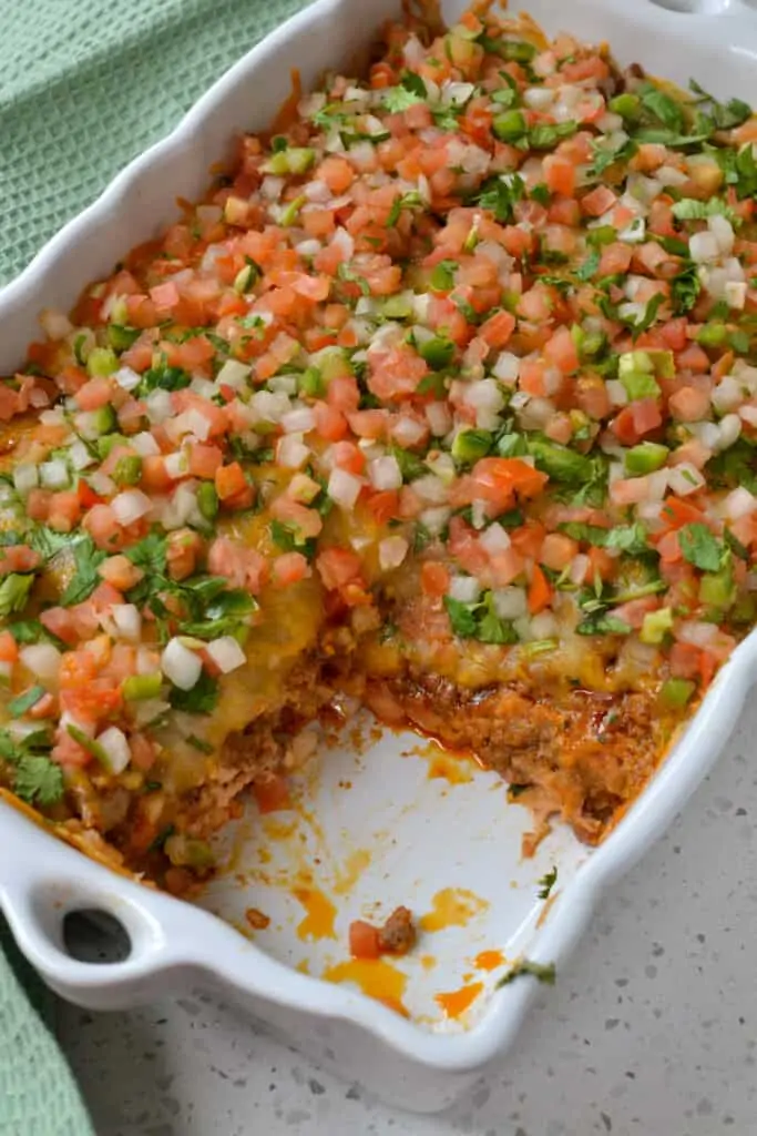 A delicious and easy layered Taco Casserole with chips, refried beans, taco seasoned ground beef, oodles of cheese, cilantro, and Pico de Gallo.  