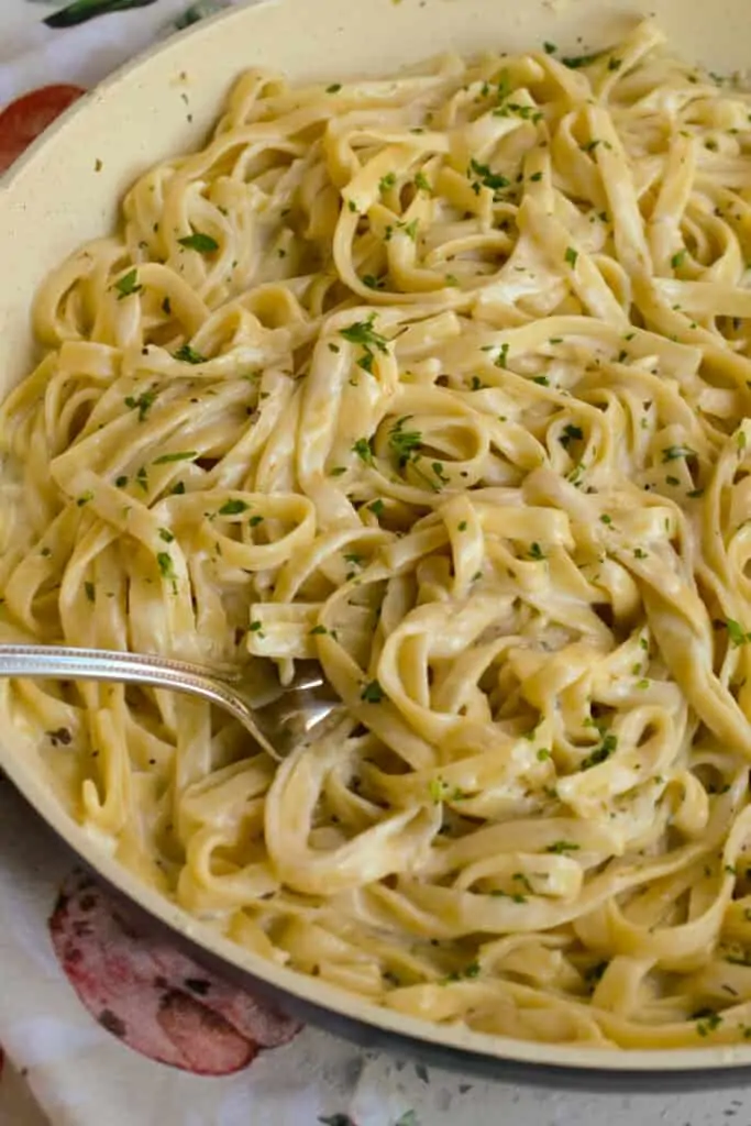 A large skillet full of pasta with alfredo sauce. 
