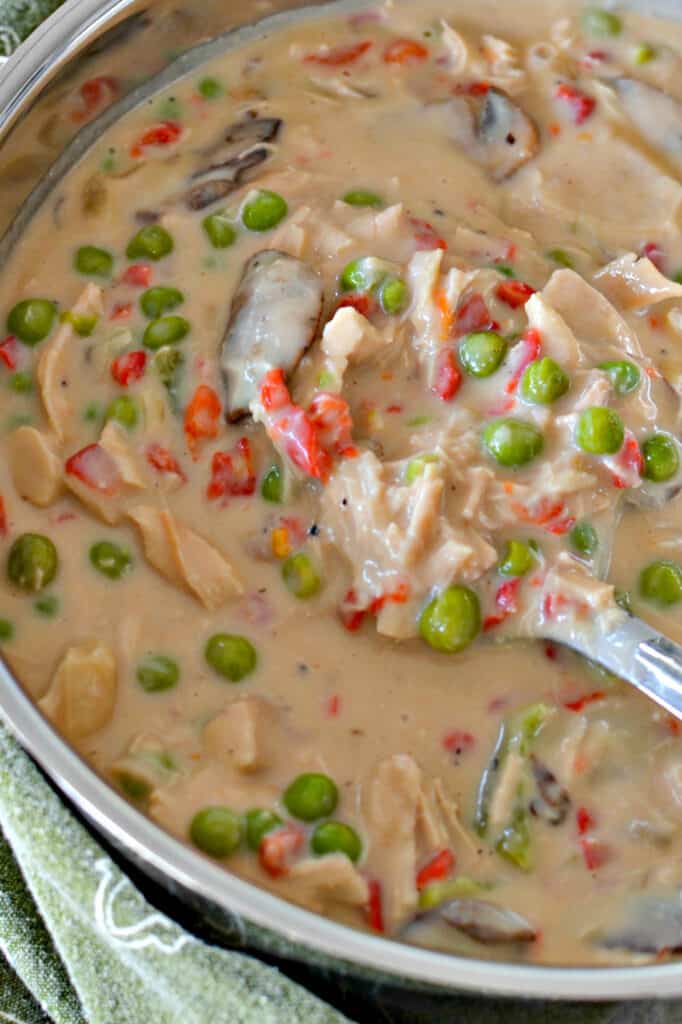 A pot full of chicken a la king with mushrooms, peas, and pimentos. 