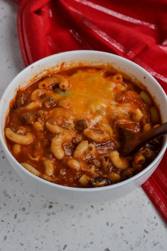 A bowl full of chili mac topped with Cheddar and Monterey Jack Cheese. 