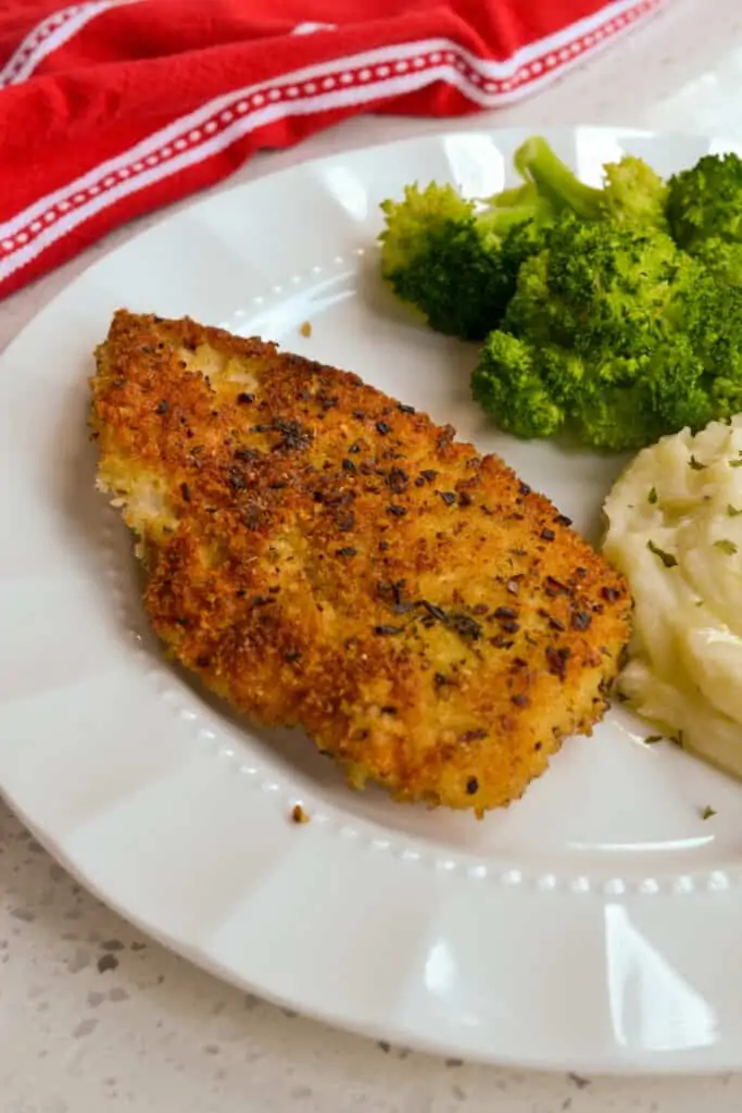 Crisp Parmesan Crusted Chicken on a dinner plate with mashed potatoes and broccoli. 