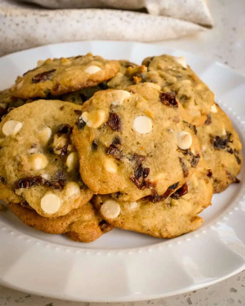 A close up view of white chocolate cranberry cookies on a white serving plate.