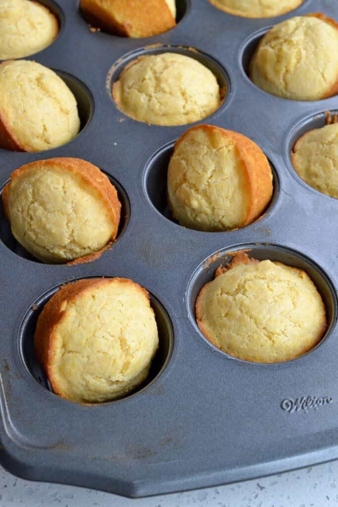 A muffin tin full of fresh baked corn muffins.
