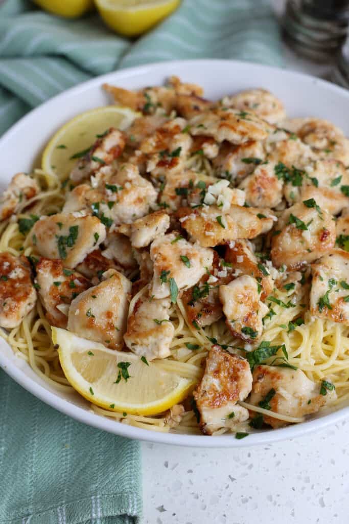Chicken scampi over thin spaghetti with fresh lemon wedges.  