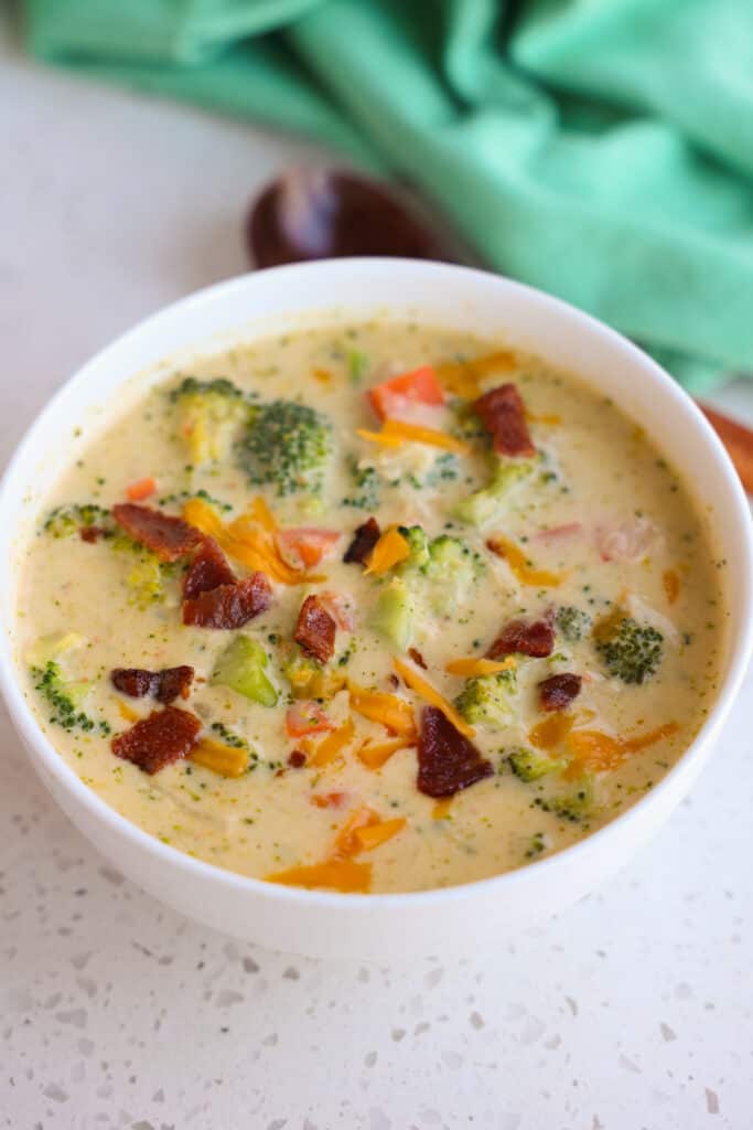A bowl full of broccoli cheese soup topped with bacon crumbles.   