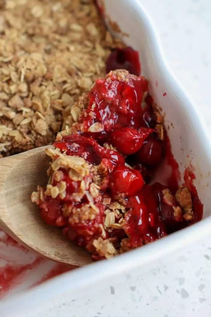 A spoon full of homemade cherry crisp. 