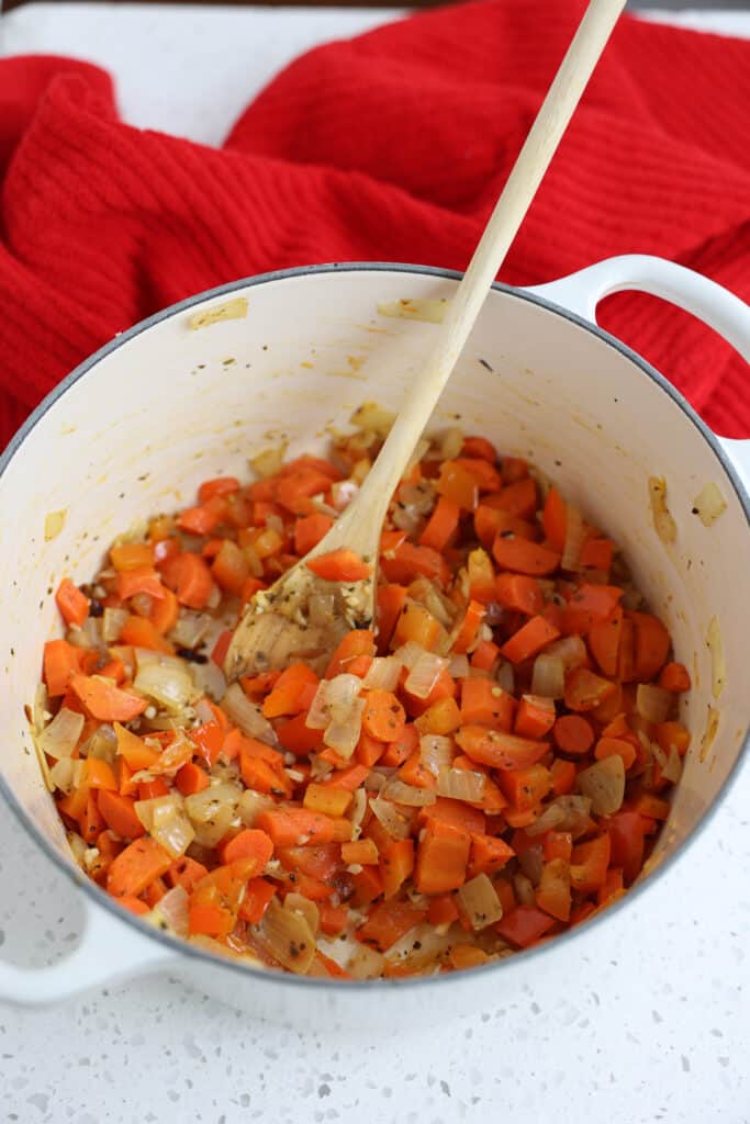 Cook the onions, bell peppers, carrots, and garlic in a large heavy pot.