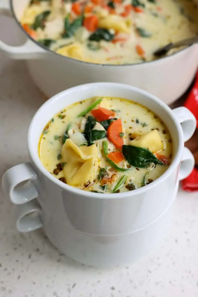 A bowl full of creamy spinach, chicken, and cheese tortellini soup. 