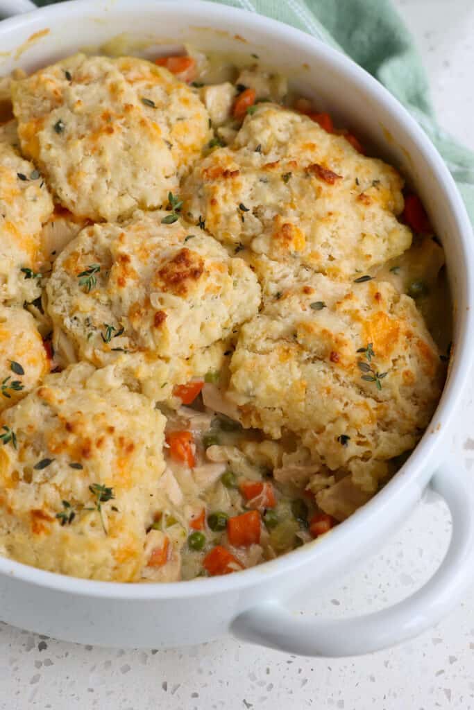 A casserole full of roasted chicken, vegetables, and gravy with fresh warm biscuits. 