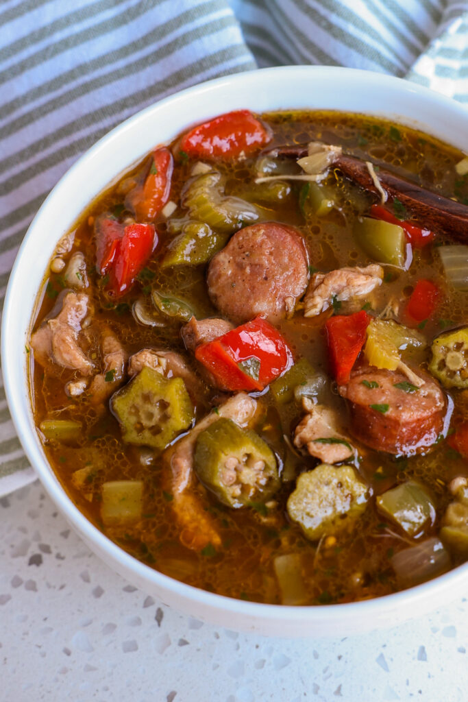 A bowl full of chicken and andouille sausage gumbo with onions, celery, bell pepper and okra. 