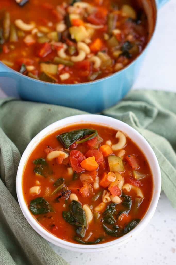 A bowl full of traditional minestrone with beans, elbow pasta and spinach.  