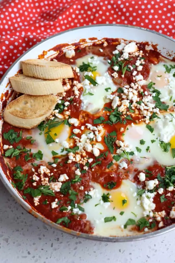 A skillet full poached eggs in tomato sauce. 