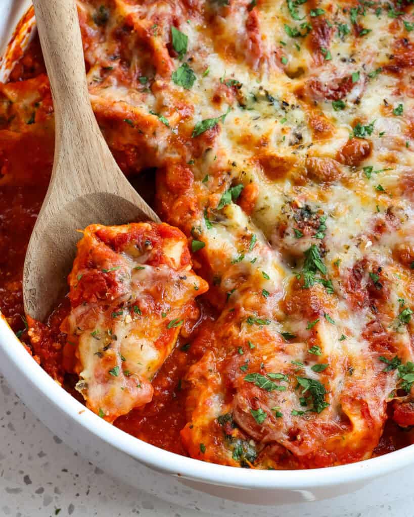 A round casserole dish full of ricotta and spinach stuffed shells. 