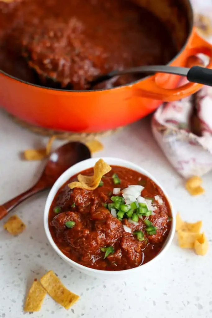 A bowl full of authentic Texas Chili topped with minced onion and jalapeno. 