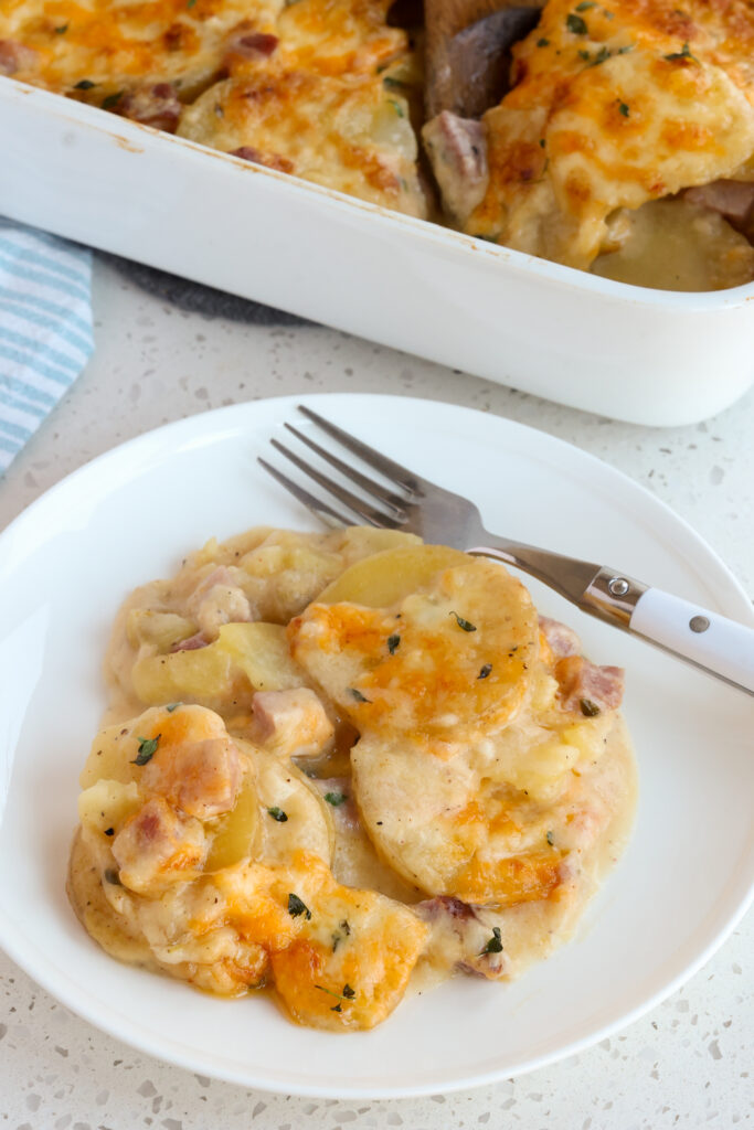 A serving plate full of scalloped potatoes and ham.  